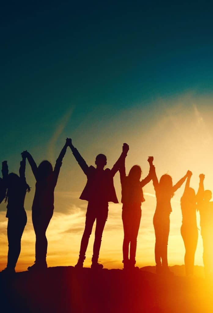 Silhouette of a group holding hands against a sunset sky