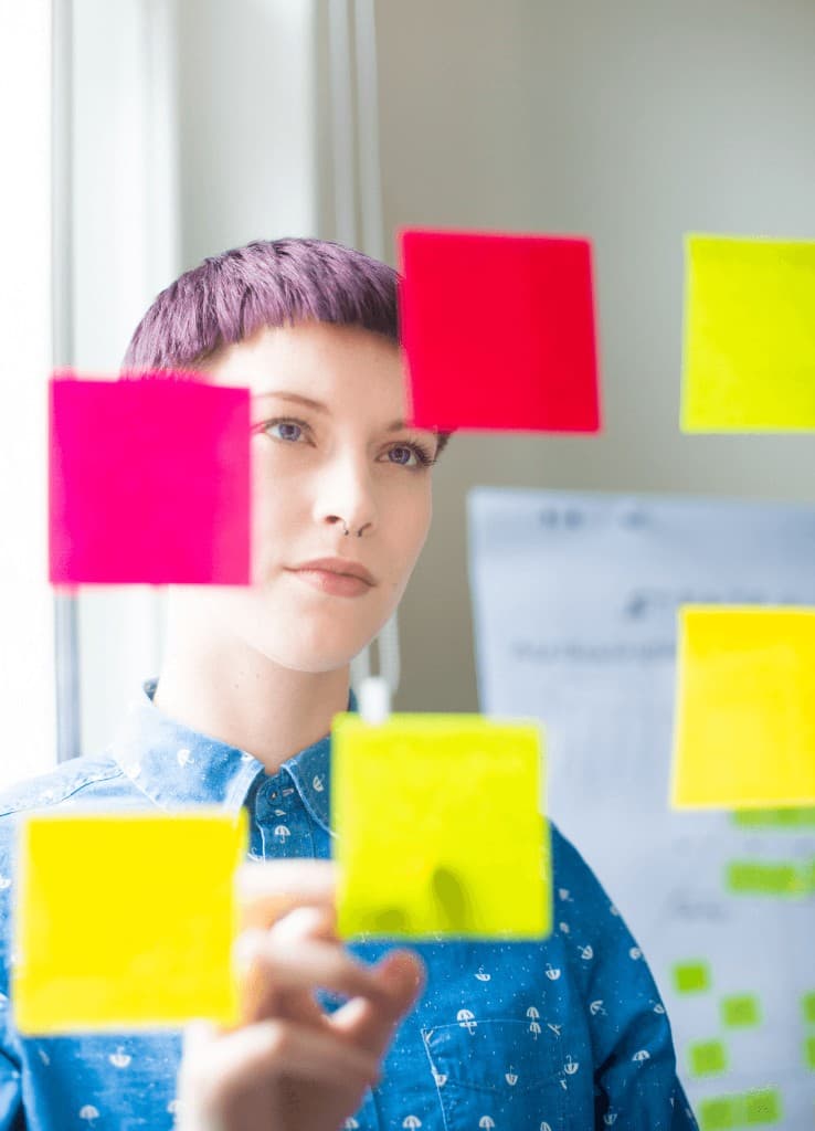 Person looking through a glass wall covered in colourful sticky notes