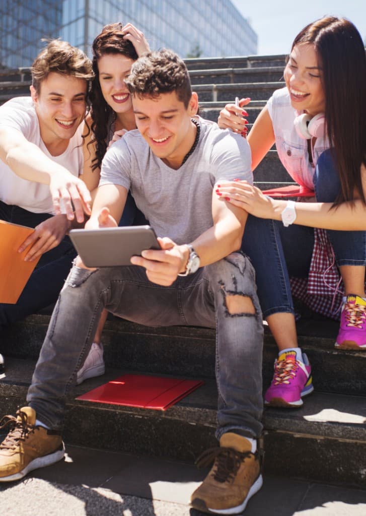 Young people sitting on outdoor steps looking at a tablet together