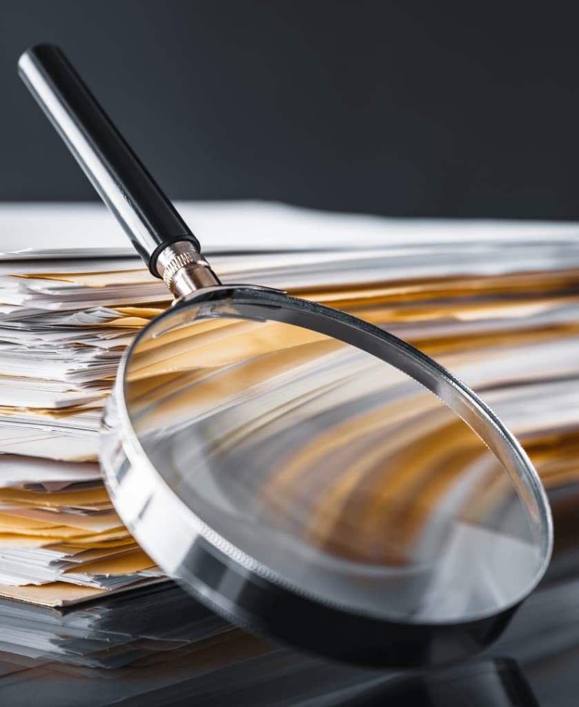 Magnifying glass resting on a stack of documents