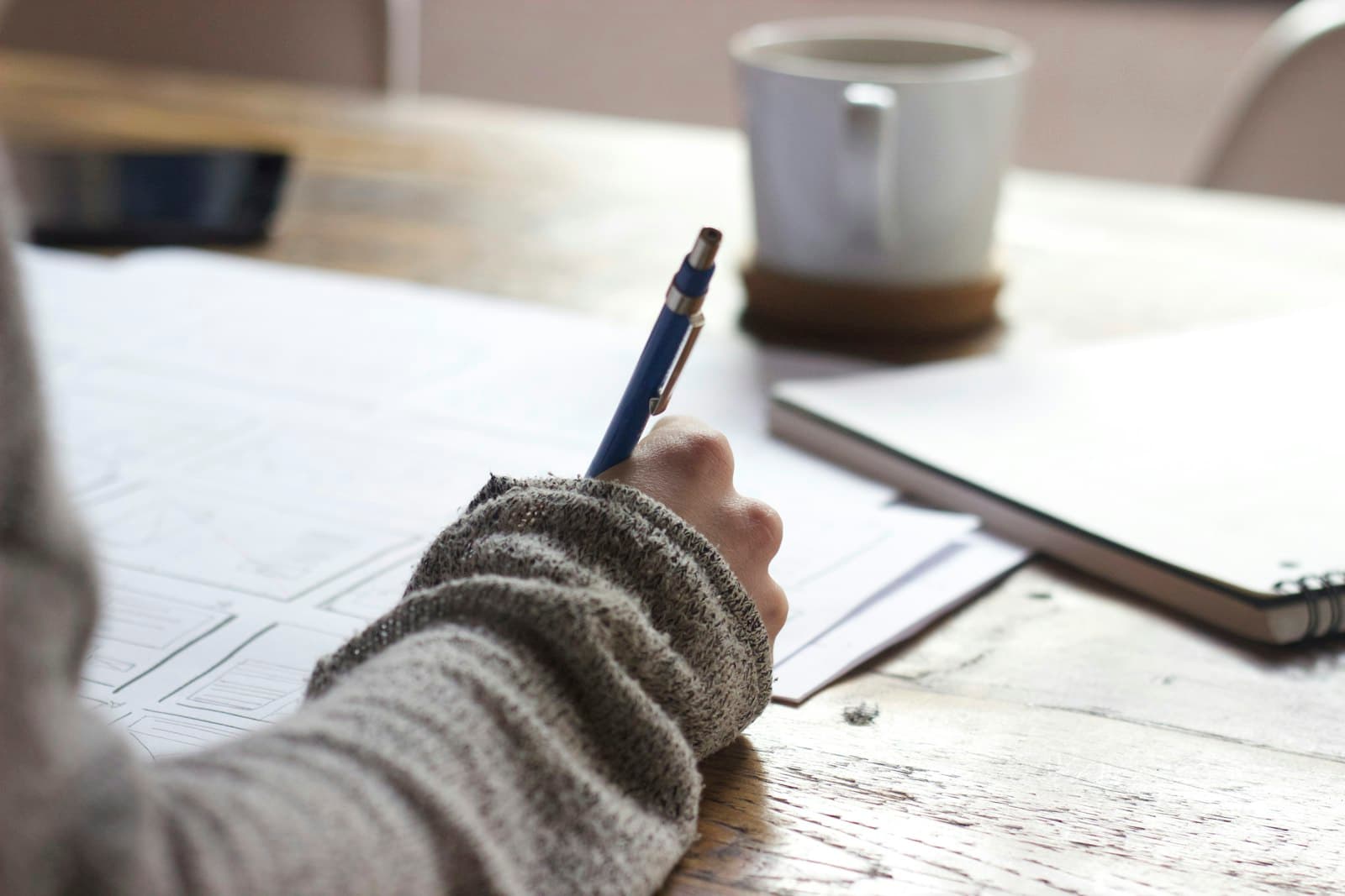 Person writing and researching at a desk