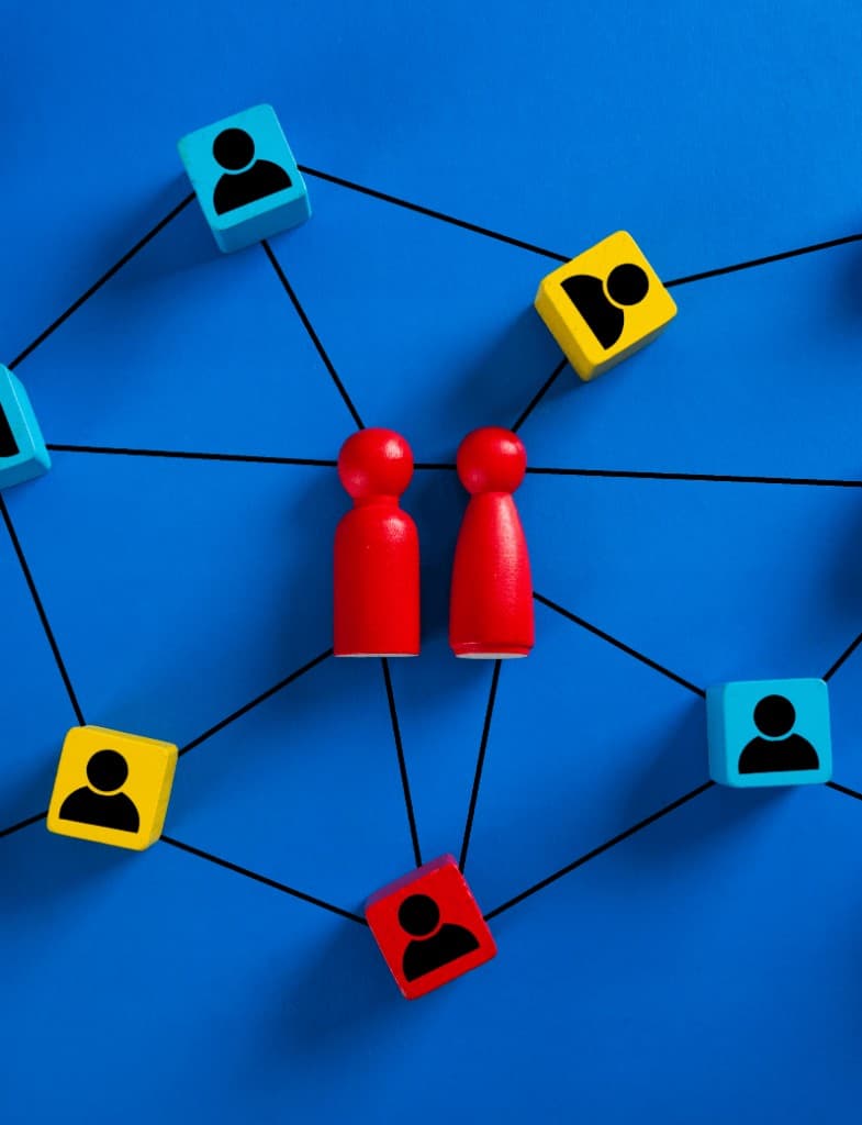 Wooden figures and blocks connected by lines on a blue background, representing people and roles in an organisation